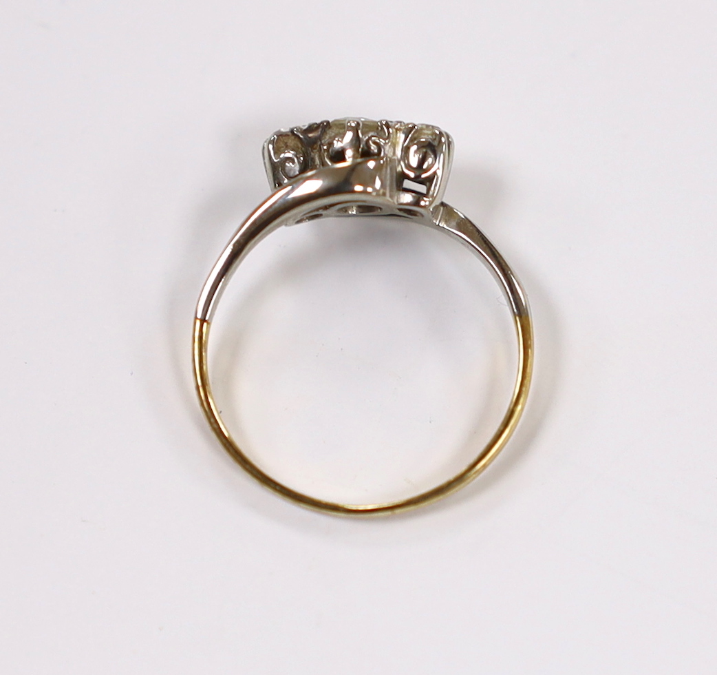 A yellow metal and three stone diamond set crossover ring, size H/I, gross weight 2 grams.